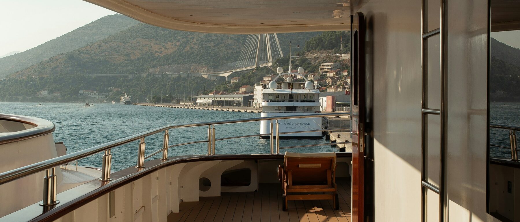Golden-hour view down the teak deck of a superyacht